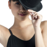A young asian woman poses with a top hat against white background