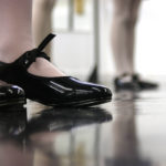 A group of girls in dance class - close up on the tap shoes and the reflections in the floor.