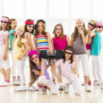 Large group of little hip hop dancers standing and looking at the camera. Some of them are holding a radio.